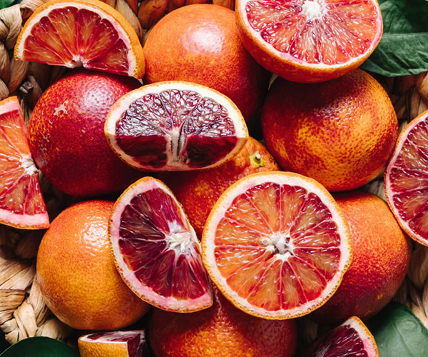 Girls show fruit crates full of oranges